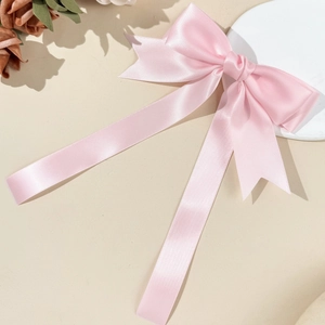 Dettaglio del fiocco per capelli in raso rosa con nastri su un vassoio decorato