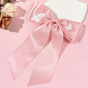 Vue détaillée d'une pince à cheveux avec nœud en satin rose et rubans sur plaque de pierre