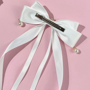 Detailansicht der weißen Satin-Haarschleife mit Perlenanhängern und langen Bändern