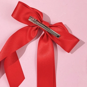 Detail of red satin bow hair clip featuring a secure silver metal alligator clamp