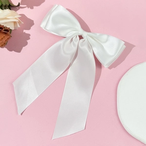 Barrette à grand nœud en satin blanc avec rubans sur un fond rose poudré délicat