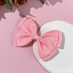 Pink double-layered grosgrain bow hair clip for girls on a stone display pedestal