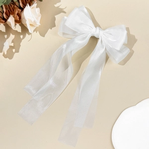 Detail von weißer Organza-Schleife Haarspange mit langen Bändern auf beigem Hintergrund