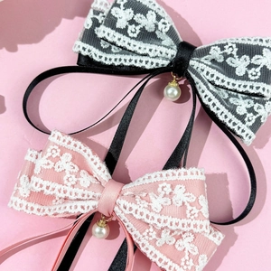 Detail of pink and black lace bow hair clips with silk ribbons and pearl pendants