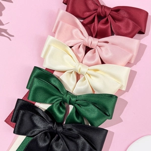 Detail view of five satin bow hair clips in burgundy pink cream green and black colors