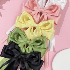 Close-up of satin ribbon bow hair clips in pink, yellow, green, black and white colors
