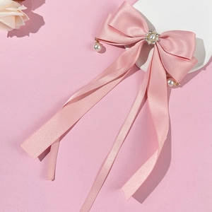 Detail der rosa Satin-Schleifen-Haarklammer mit Strasssteinen und eleganten Perlenanhängern