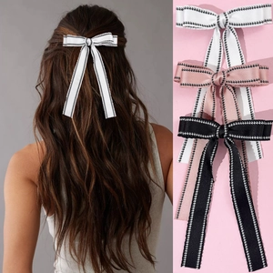 Close-up of elegant bow hair clips with long ribbons in white, pink, and black colors