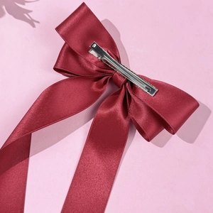 Close-up of the silver metal duckbill clip on a dark red satin ribbon bow hair accessory