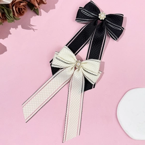 Barrettes à nœuds élégantes en soie noire et crème avec perles sur fond rose pastel