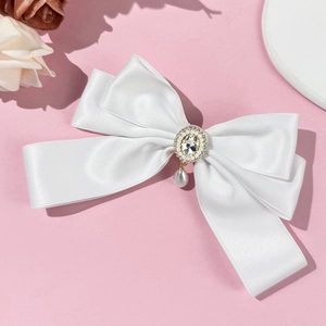 Detail of white satin bow hair clip with rhinestone center and teardrop pearl pendant