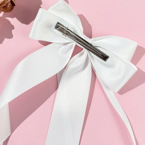 Close-up of white satin bow hair clip with silver stainless steel duckbill clip