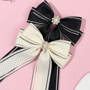 Détail de barrettes à nœud en tissu avec motif à carreaux, perles et strass brillants