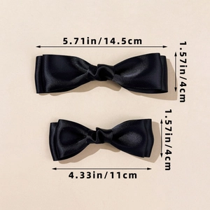 Detail view of two black satin double-layered bow hair clips with size measurements