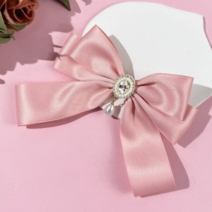 Detail of pink satin bow hair clip with crystal metal centerpiece and pearl drop