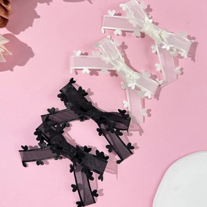 Détail de quatre barrettes à nœuds en organza avec motifs de cœur en noir et blanc