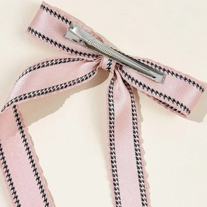 Detail of pink satin bow hair clip with houndstooth trim and silver metal duckbill clip