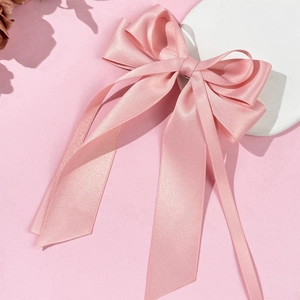 Close-up of pink satin bow hair clip with elegant long ribbons and silky glossy texture
