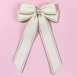 Détail du nœud en ruban blanc crème avec rayures roses et centre en perle cristalline