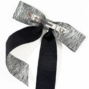 Dettaglio della clip per capelli a fiocco in tessuto pieghettato argento e nero metallizzato