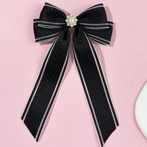 Détail d'une pince à cheveux à nœud noir avec perle d'imitation et strass