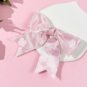 Rosa Satin-Schleifen-Haarspange mit Kleeblatt-Jacquard auf einem dekorativen Tablett