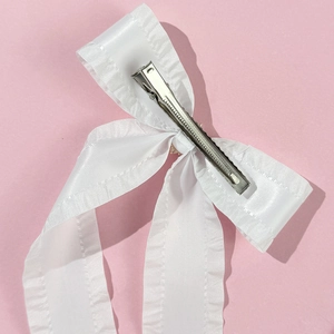 Nahaufnahme der weißen Satin-Haarschleife mit Rüschenkanten und silbernem Metallclip
