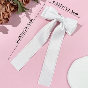 Detail view of white ribbon bow hair clip with wavy edges and dimensions 23.5cm by 12.5cm