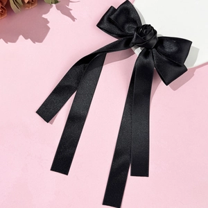 Détail d'un nœud papillon en satin noir élégant avec rose faite main et longs rubans fluides