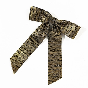 Fermaglio per capelli a fiocco plissettato oro e nero con texture metallica su fondo bianco