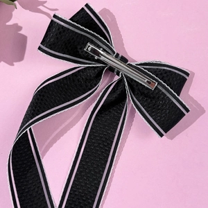 Détail d'un nœud papillon noir avec rayures roses et pince à bec de canard en métal argenté