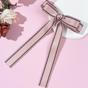 Detail of pink satin ribbon hair clip with black dotted edges and long flowing streamers