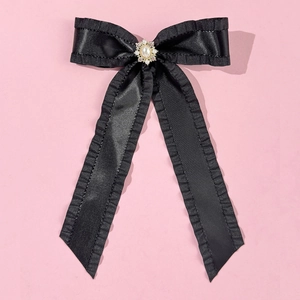 Detailaufnahme der schwarzen Satin-Haarschleife mit Perle, Strass und Rüschenkanten