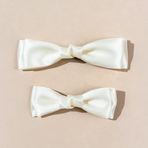 Detail of cream silk satin double-layered bow hair clips with smooth glossy texture