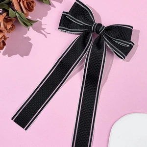 Détail d'un nœud papillon noir à texture gaufrée avec des rayures roses et longs rubans
