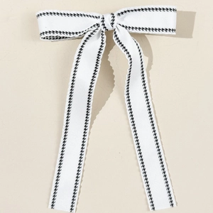 Close-up of white woven ribbon bow with classic black houndstooth pattern edges