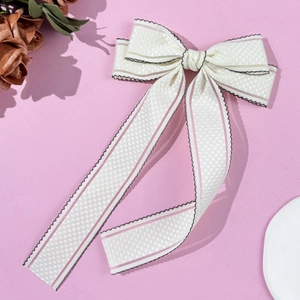 Gros plan d'un nœud papillon crème avec rayures roses et bords noirs ondulés sur fond rose