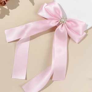 Pink satin bow hair clip with pearls and rhinestones on a minimalist background