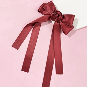 Détail d'une pince à cheveux nœud satin rouge vin avec rose 3D et longs rubans soyeux