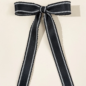 Detailed close-up of a classic black ribbon bow with white houndstooth check edge trim