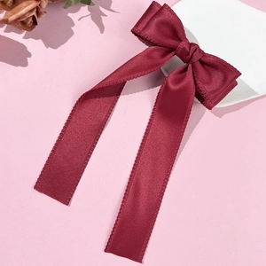 Detail of burgundy satin bow hair clip featuring elegant long ribbons and fine stitching