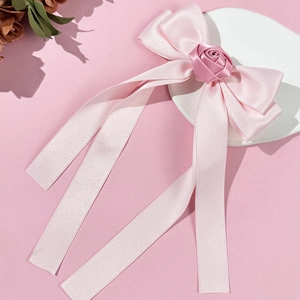 Détail d'une pince à cheveux en satin rose avec rose en soie et longs rubans fluides