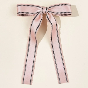 Detailed view of pink satin ribbon hair clip with black houndstooth patterned edges
