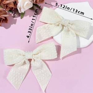 Dettaglio dimensioni dei fermagli a fiocco in tweed bianco sporco, larghi 13 cm e alti 11 cm