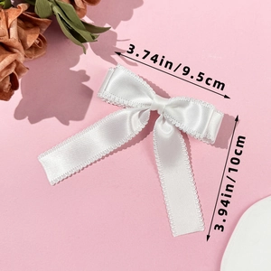 Detailed size view of white satin bow hair clip with scallop lace edge on pink backdrop
