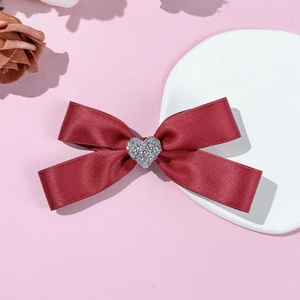 Detailed close-up of dark red satin bow hair clip with a silver heart rhinestone center