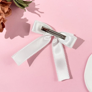 Detail view of white satin bow hair clip with lace trim and silver metal duckbill clip