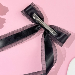 Detail of the black satin bow hair clip with purple gauze edge and metal alligator clip