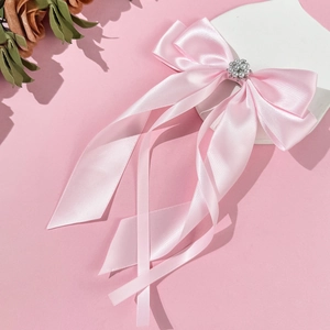 Dettaglio del fiocco in raso rosa con nastri lunghi e decorazione elegante con perle