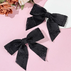 Dettaglio di fermagli per capelli a fiocco nero con texture lucida e code lunghe